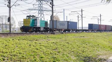 Goederentrein met containers rijdt over een spoorlijn.