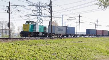 Goederentrein met containers rijdt over een spoorlijn.