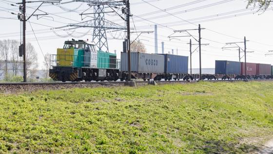 Goederentrein met containers rijdt over een spoorlijn.