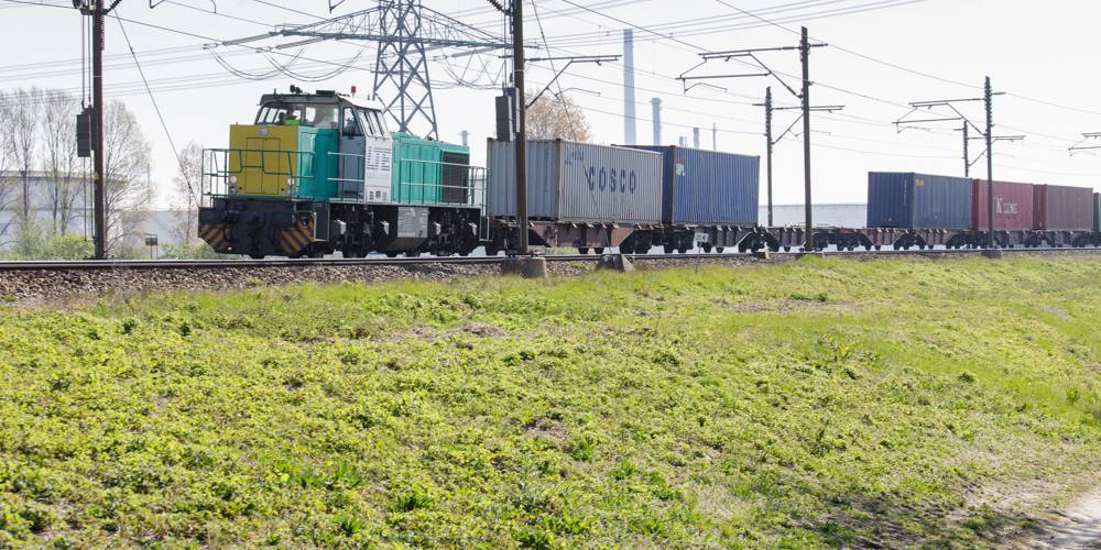 Goederentrein met containers rijdt over een spoorlijn.