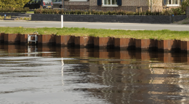 Foto van sloot met bruine muur tussen water en oever