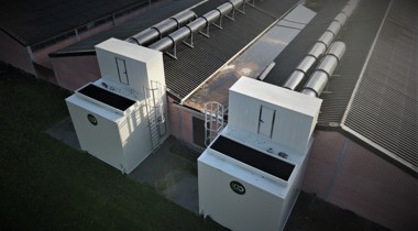 Grote witte kasten naast een groot gebouw met noodtrappen eraan