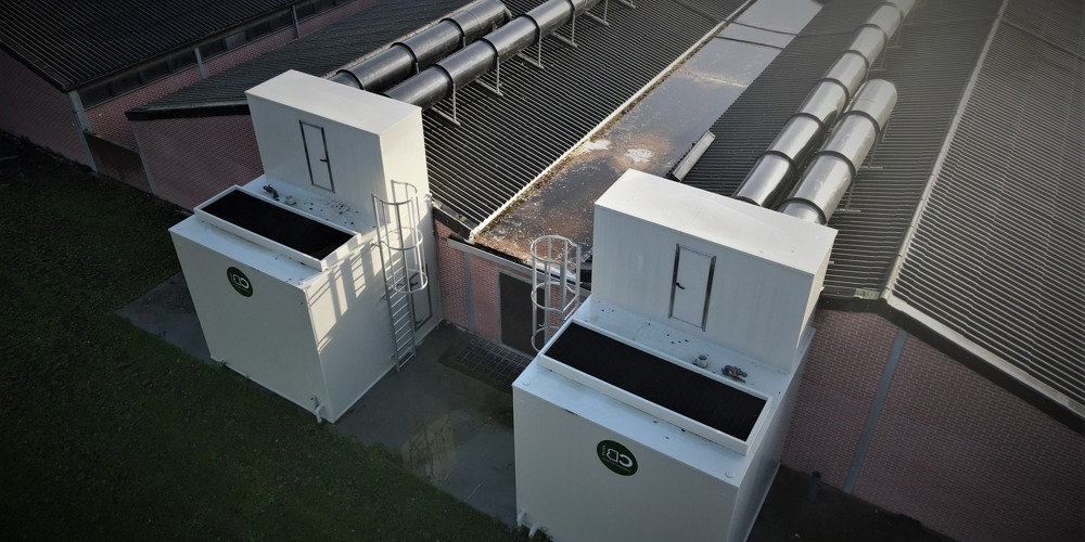 Grote witte kasten naast een groot gebouw met noodtrappen eraan