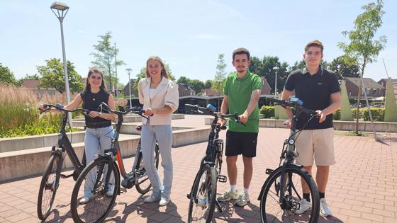 Vier scholieren staan op een zonnig plein naast hun fiets
