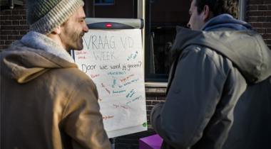 Twee mannen staan voor een flip-over waarop staat geschreven 'Vraag v/d week. Door wie word jij gezien?'