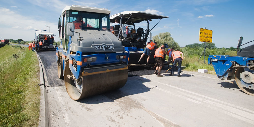 Machines die asfalteren op weg met werknemers