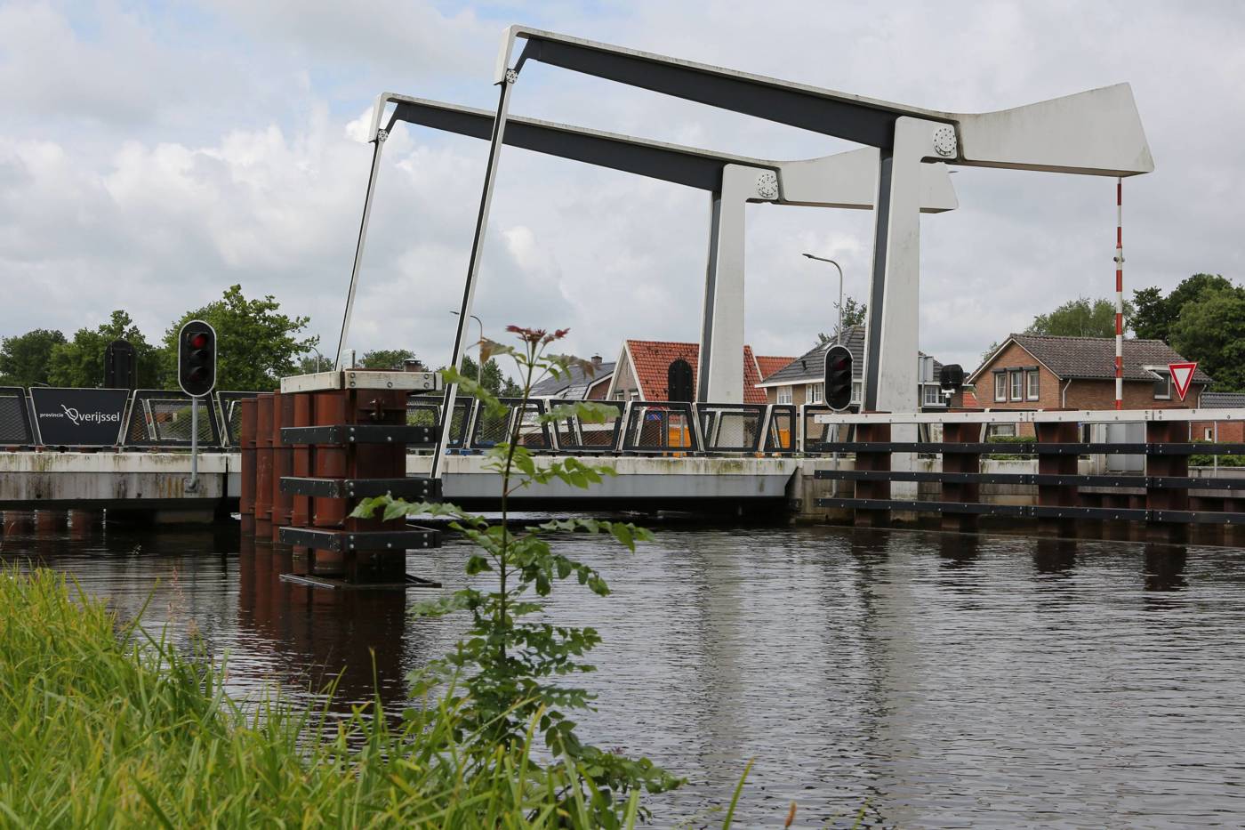 Moderne ophaalbrug met witte steunpilaren over een kanaal in woongebied.