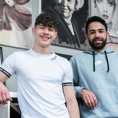 Twee vrijwilligers poseren. Ze kijken lachend in de lens.