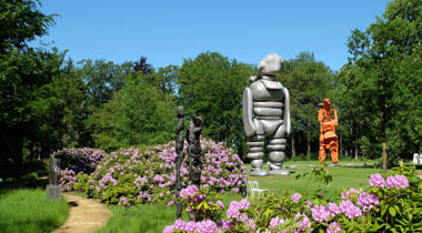 Beelden in de beeldentuin in de natuur, tussen paarse bloemenstruiken en omringd door bomen