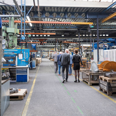 Mensen lopen in groepje door indoor werkgebied met machines