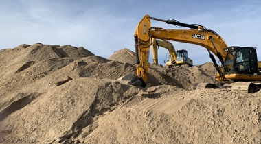 Graafmachines tussen heuvels zand en aarde op bouwterrein