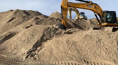 Graafmachines tussen heuvels zand en aarde op bouwterrein