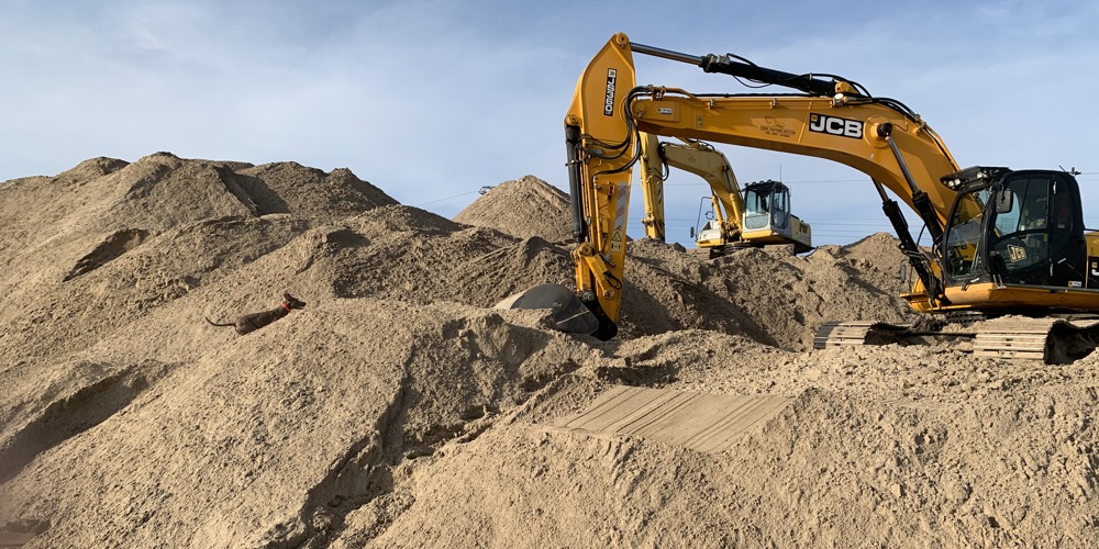 Graafmachines tussen heuvels zand en aarde op bouwterrein
