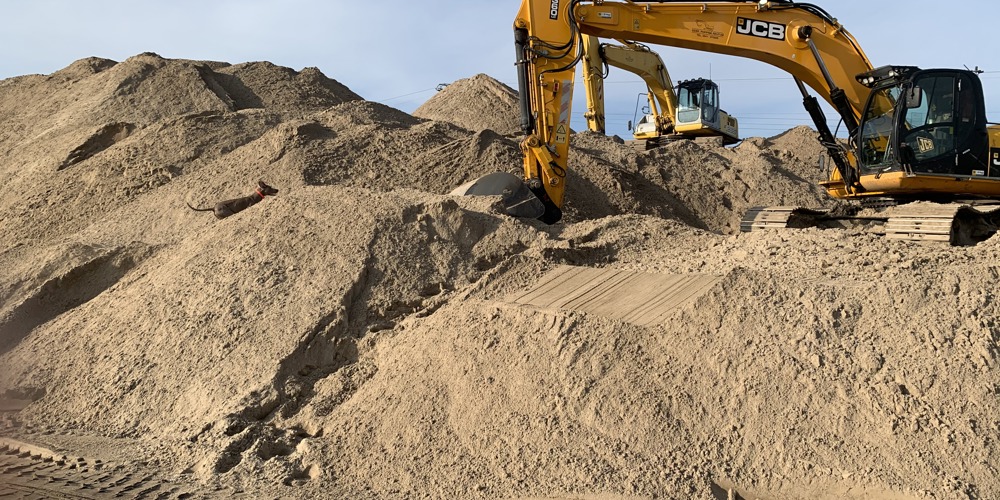 Graafmachines tussen heuvels zand en aarde op bouwterrein