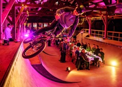 Vrijwilligersprijs. Lange tafel waar mensen een etentjes hebben. Dit alles op een soort bmx baan in een hal.