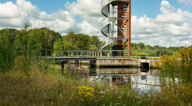 Trap naast hoge vogelspot torn naast een brug over sloot met bloemrijke overs