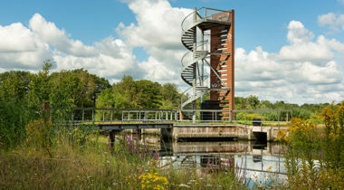Trap naast hoge vogelspot torn naast een brug over sloot met bloemrijke overs